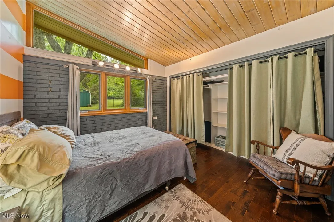 Bedroom featuring vaulted ceiling, wood-type flooring, wooden ceiling, and a closet
