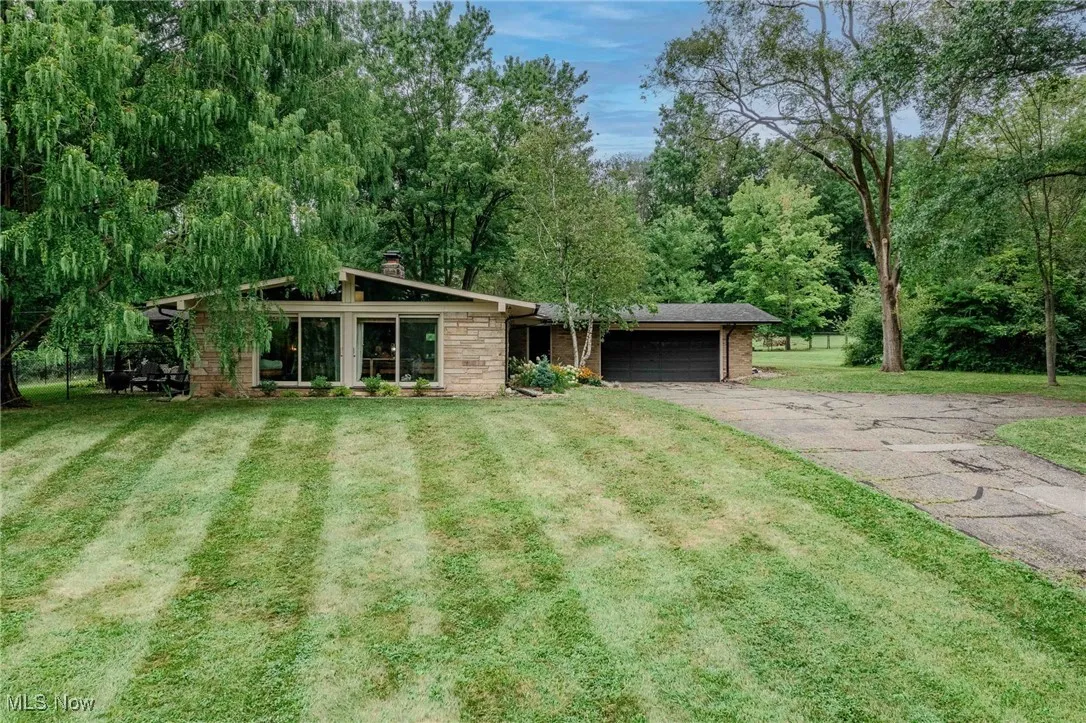 View of front of home featuring driveway, a garage, a chimney, and a front lawn