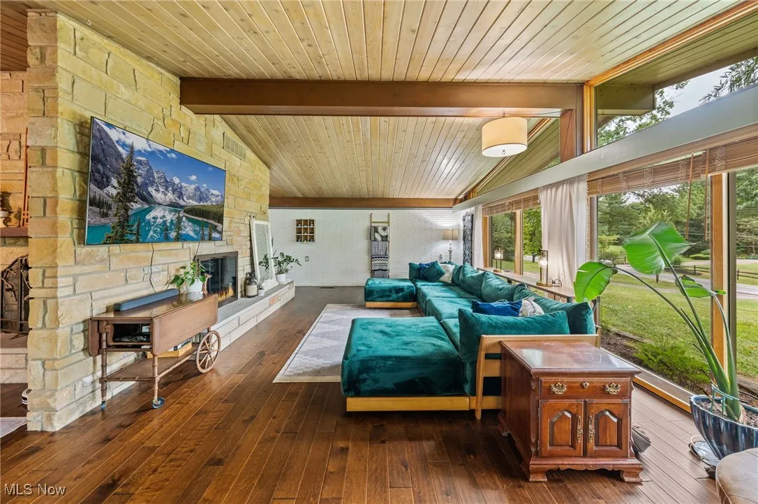 Living area with a fireplace, dark wood-type flooring, and wooden ceiling