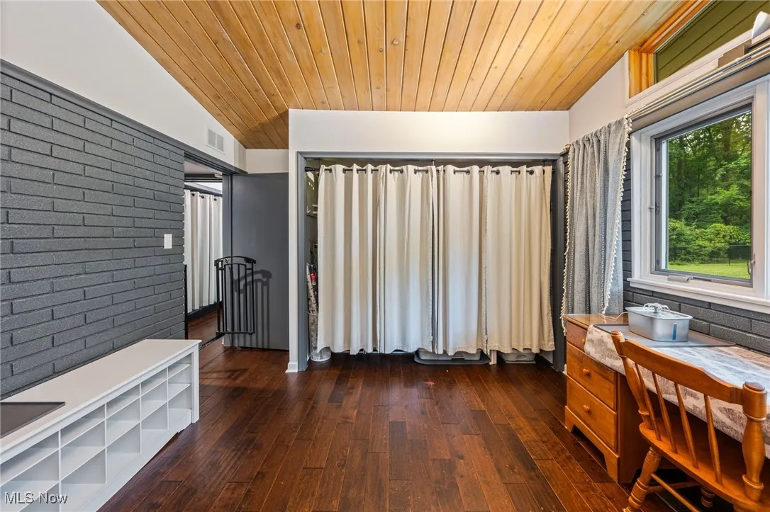 Office space featuring dark wood-style floors, brick wall, wooden ceiling, and lofted ceiling