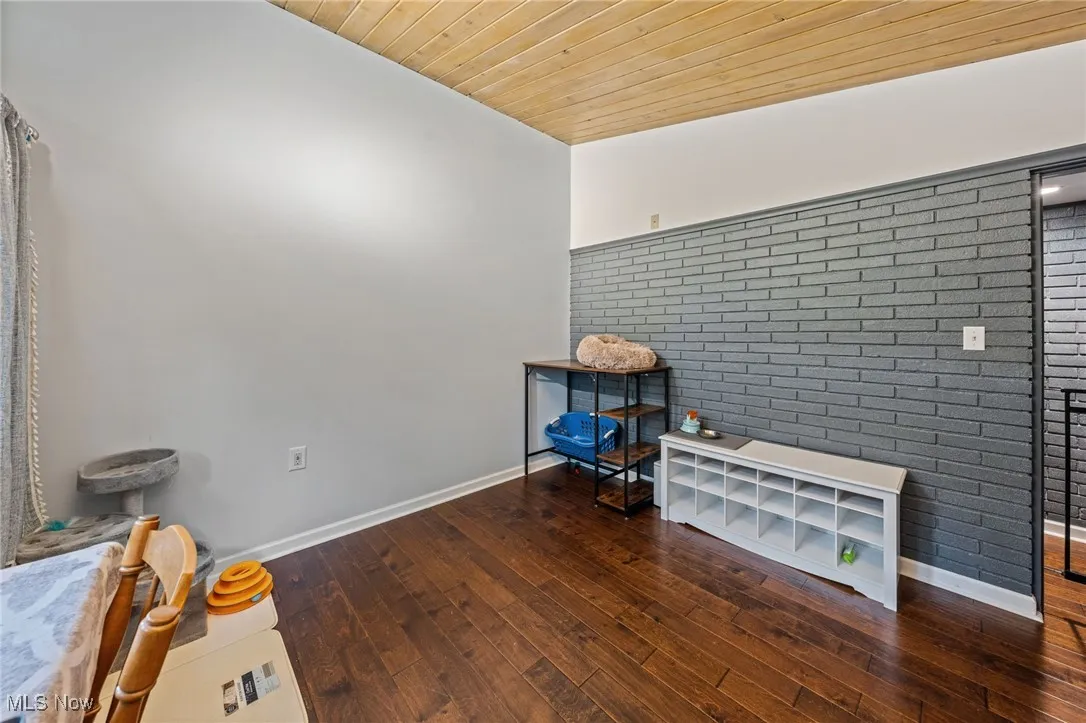 Miscellaneous room featuring wood ceiling, dark wood finished floors, and brick wall