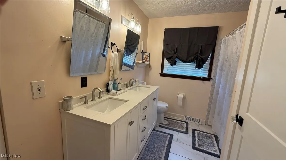 Full updated bathroom with double vanity, tiled floors