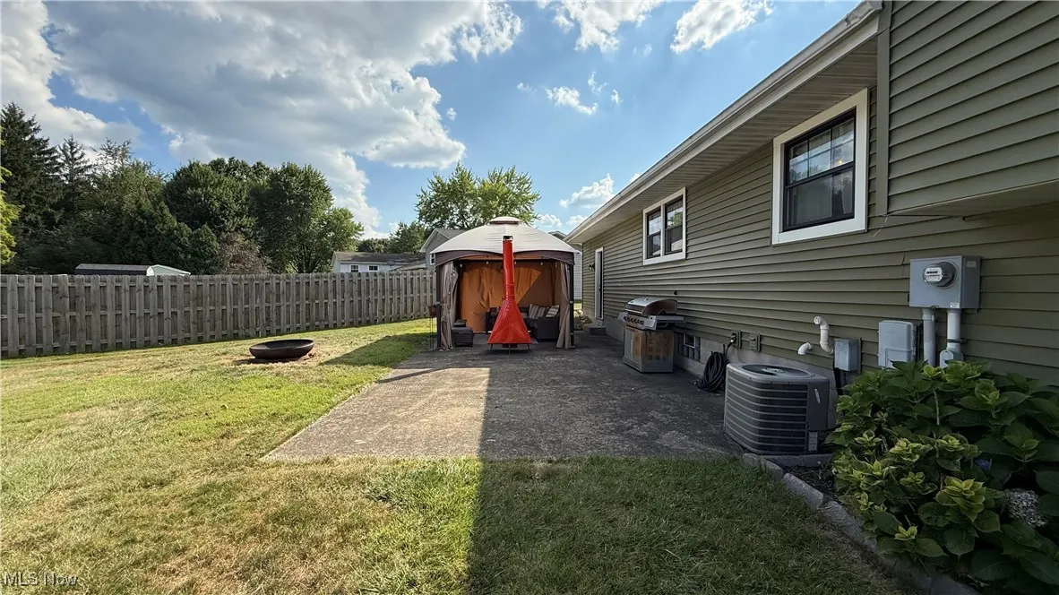 Partial fenced backyard with a patio area, an outdoor fire pit, and a hangout area
