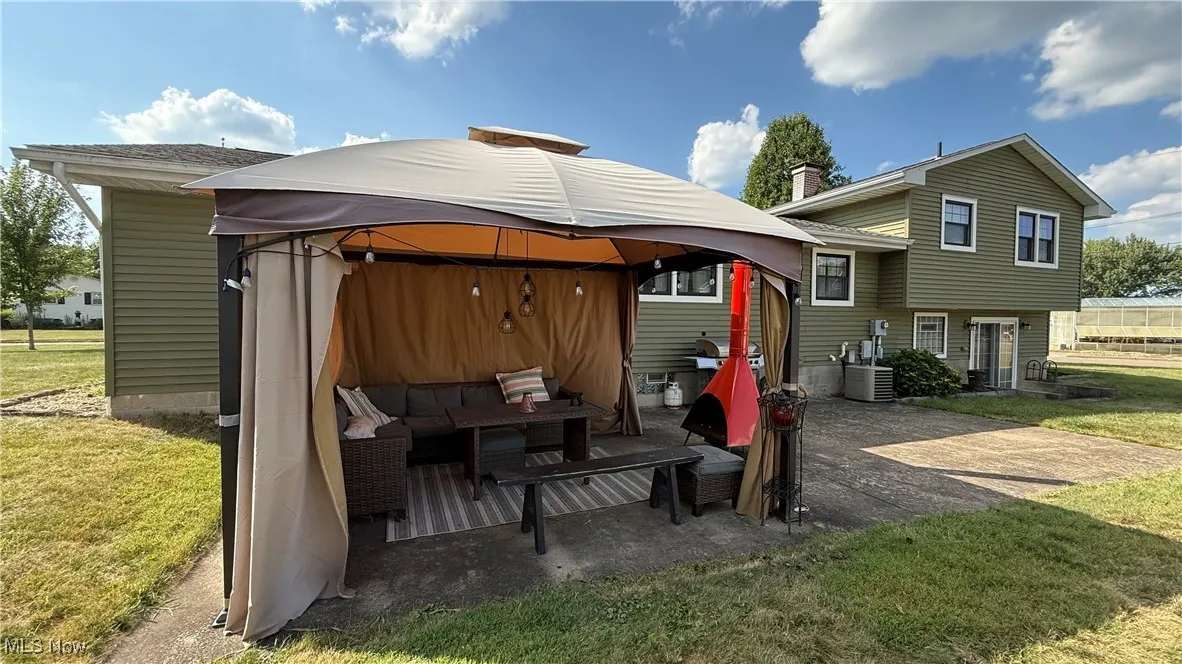 Rear view of property featuring the back yard, a patio, and an outdoor hangout area