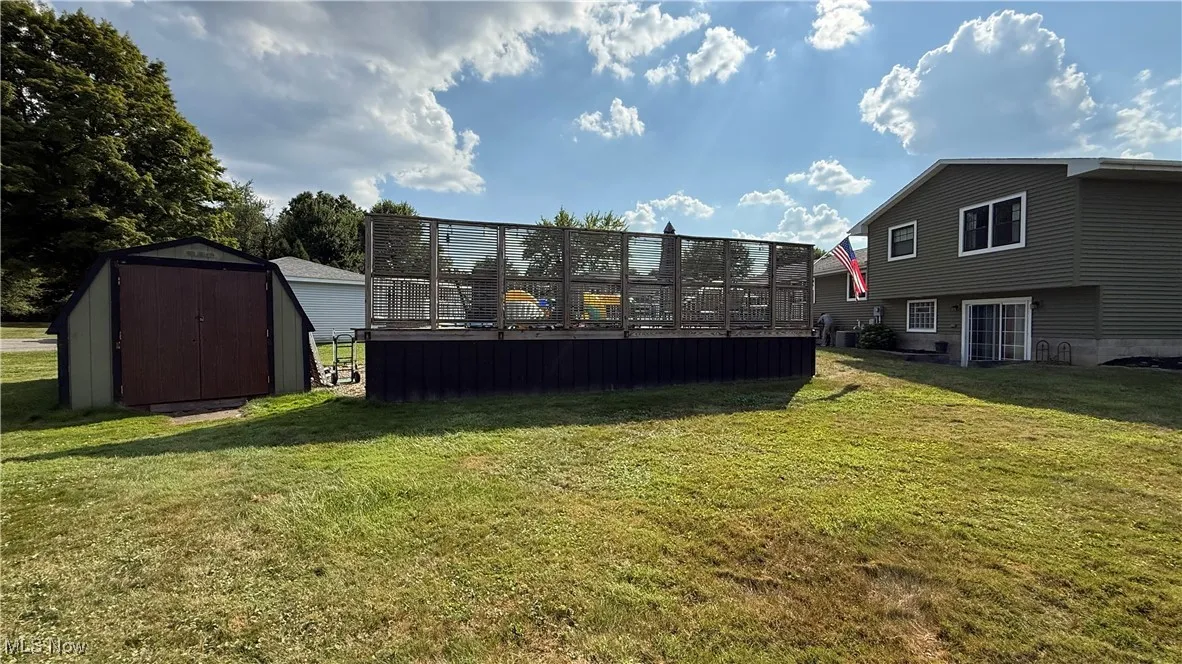 View of back yard with a wooden deck and a storage unit