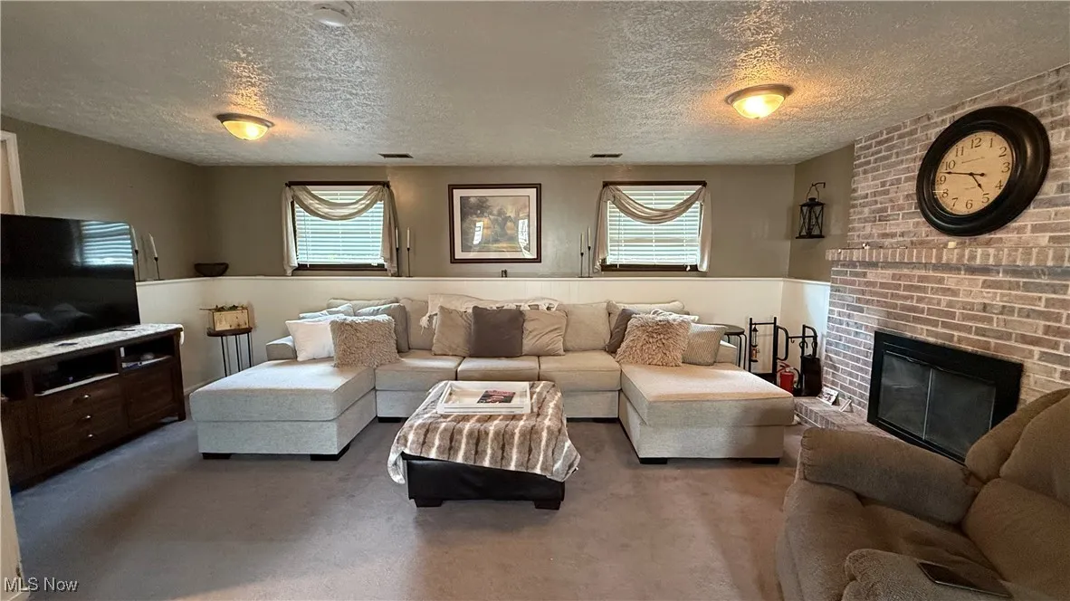 Family room with carpet, a textured ceiling, and a fireplace