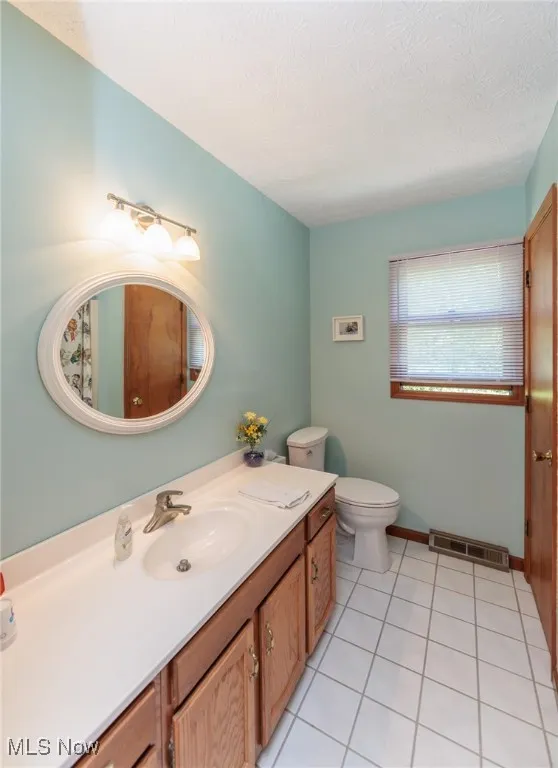 Bathroom featuring light tile patterned floors, vanity, and a textured ceiling