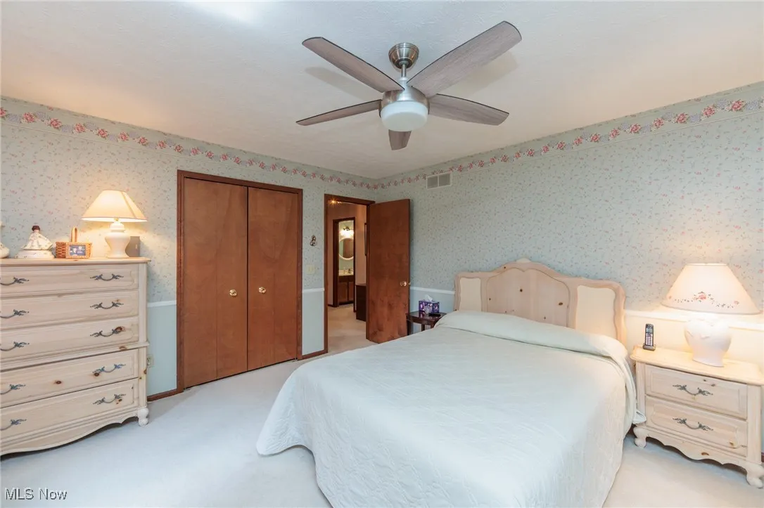 Bedroom with light colored carpet, a closet, and a ceiling fan