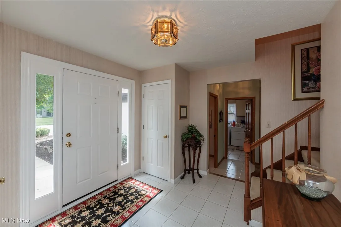 Foyer with light tile patterned floors, washer / clothes dryer, and stairway