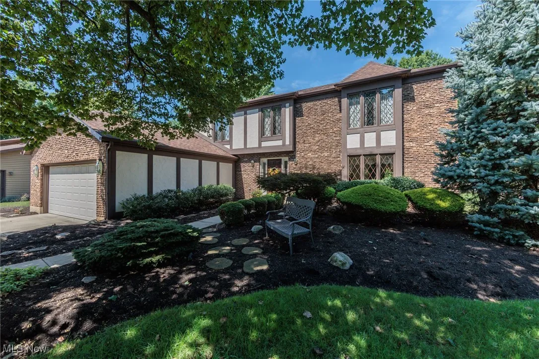 View of front of home featuring stucco siding, a garage, concrete driveway, and brick siding