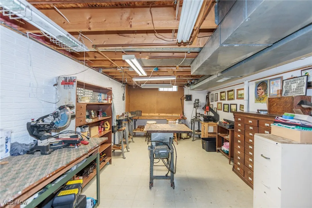 Basement featuring a workshop area, light flooring, and brick wall