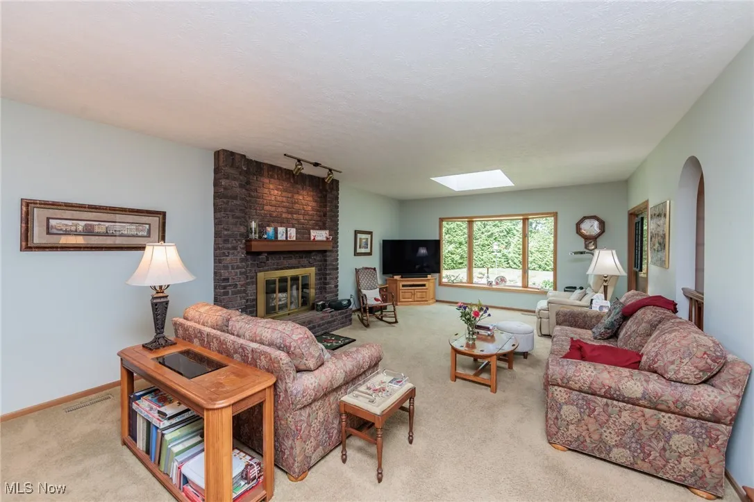 Living room featuring a skylight, light carpet, track lighting, a fireplace, and a textured ceiling