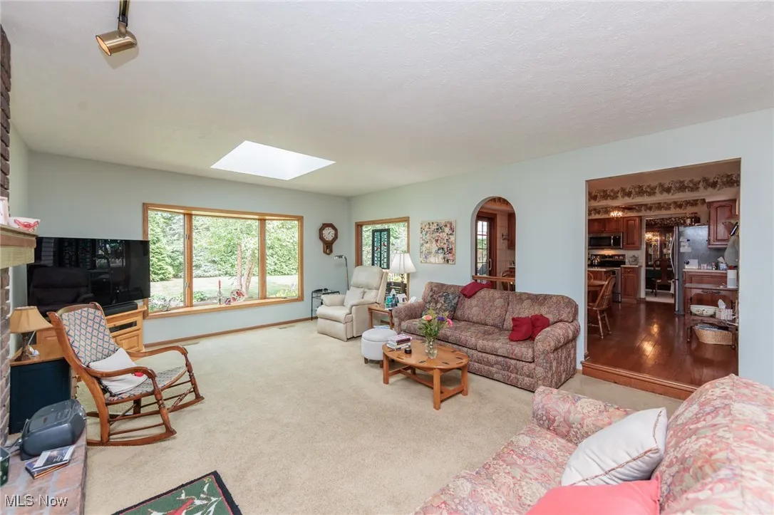 Carpeted living room featuring arched walkways, a skylight, and a textured ceiling