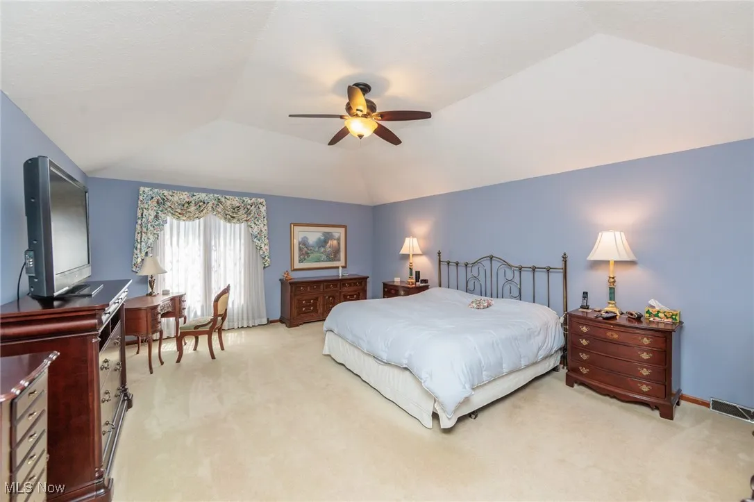Primary bedroom with carpet flooring, ceiling fan, and lofted ceiling