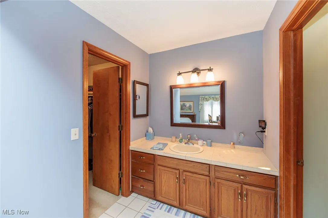Primary bathroom featuring vanity, light tile patterned floors, and a walk in closet