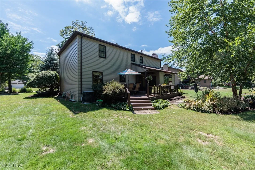 Rear view of property with a yard, a deck, and a chimney