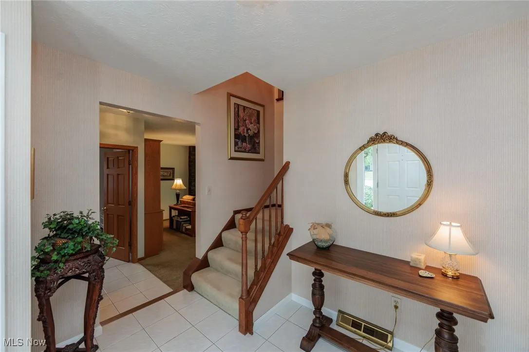 Entrance foyer featuring light tile patterned floors, a textured ceiling, and light colored carpet