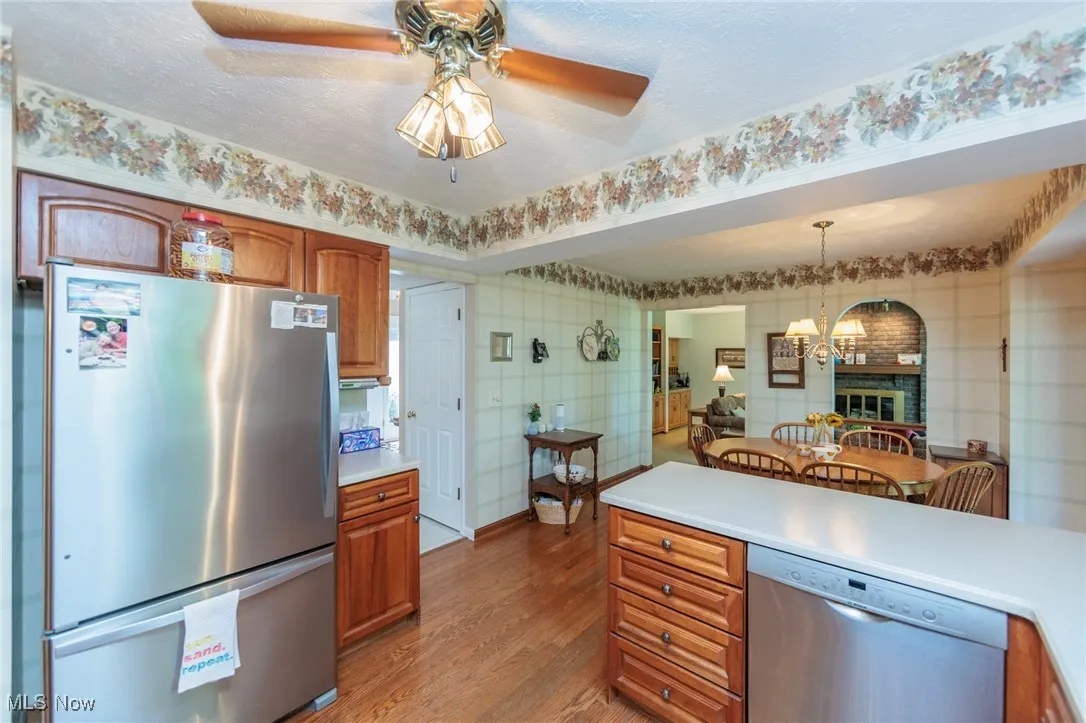 Kitchen featuring appliances with stainless steel finishes, brown cabinets, light countertops, dark wood-style flooring, and a textured ceiling