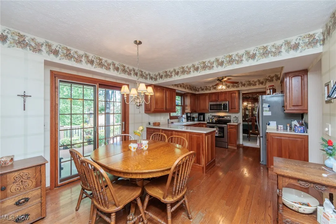 Dining space with dark wood-style flooring, a chandelier, a textured ceiling, and ceiling fan