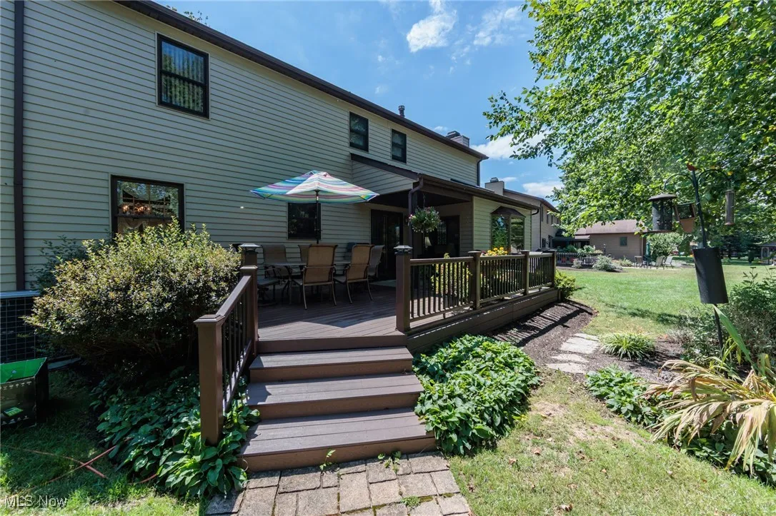 Rear view of property with outdoor dining space, a lawn, and a wooden deck