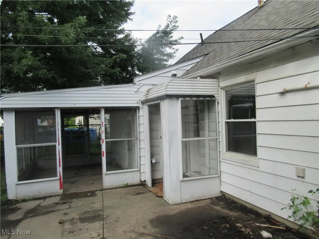 Property entrance featuring a shingled roof and a sunroom