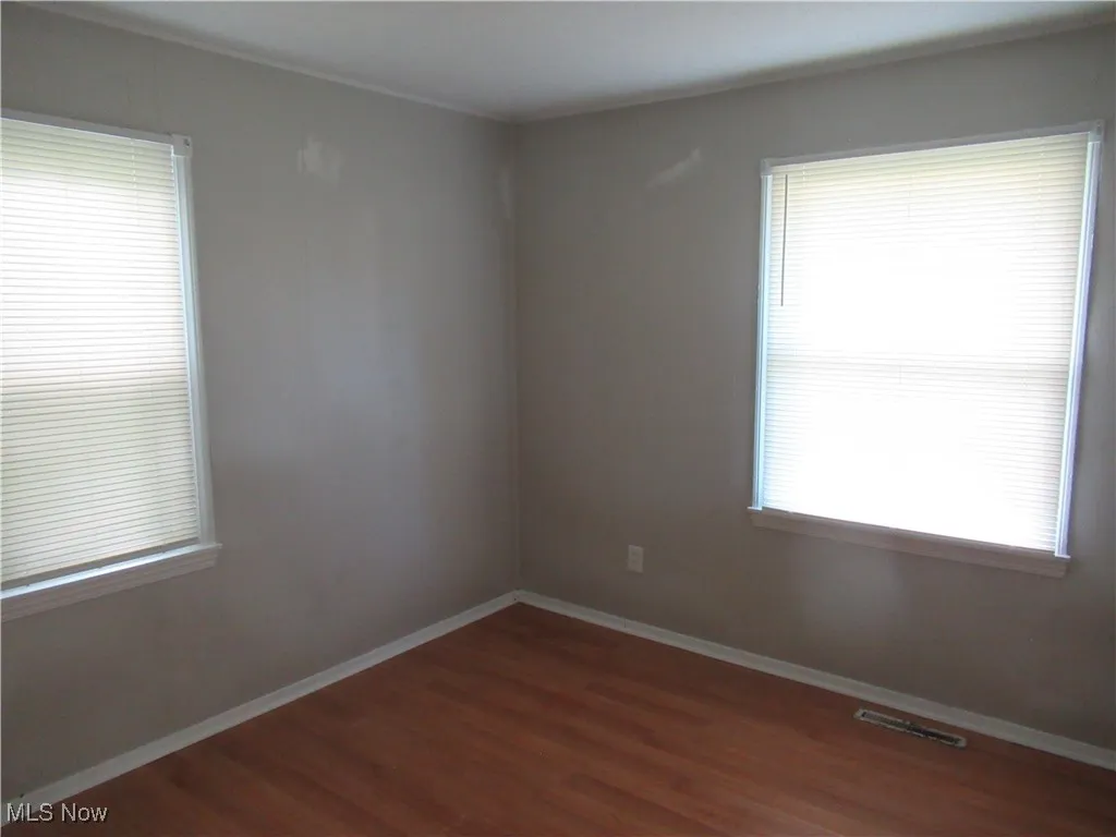Empty room with baseboards and dark wood-style flooring