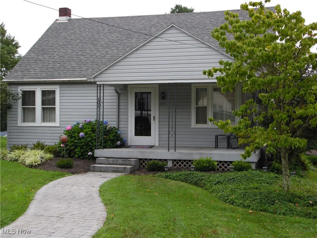 Bungalow-style house with a front lawn, a porch, a shingled roof, and a chimney