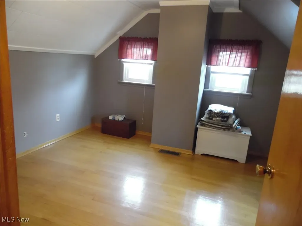 Additional living space featuring light wood-style floors and lofted ceiling