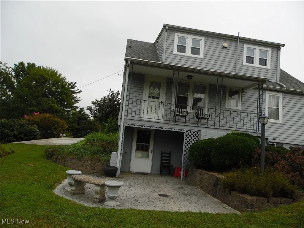 View of front of property with a patio, roof with shingles, and a front lawn