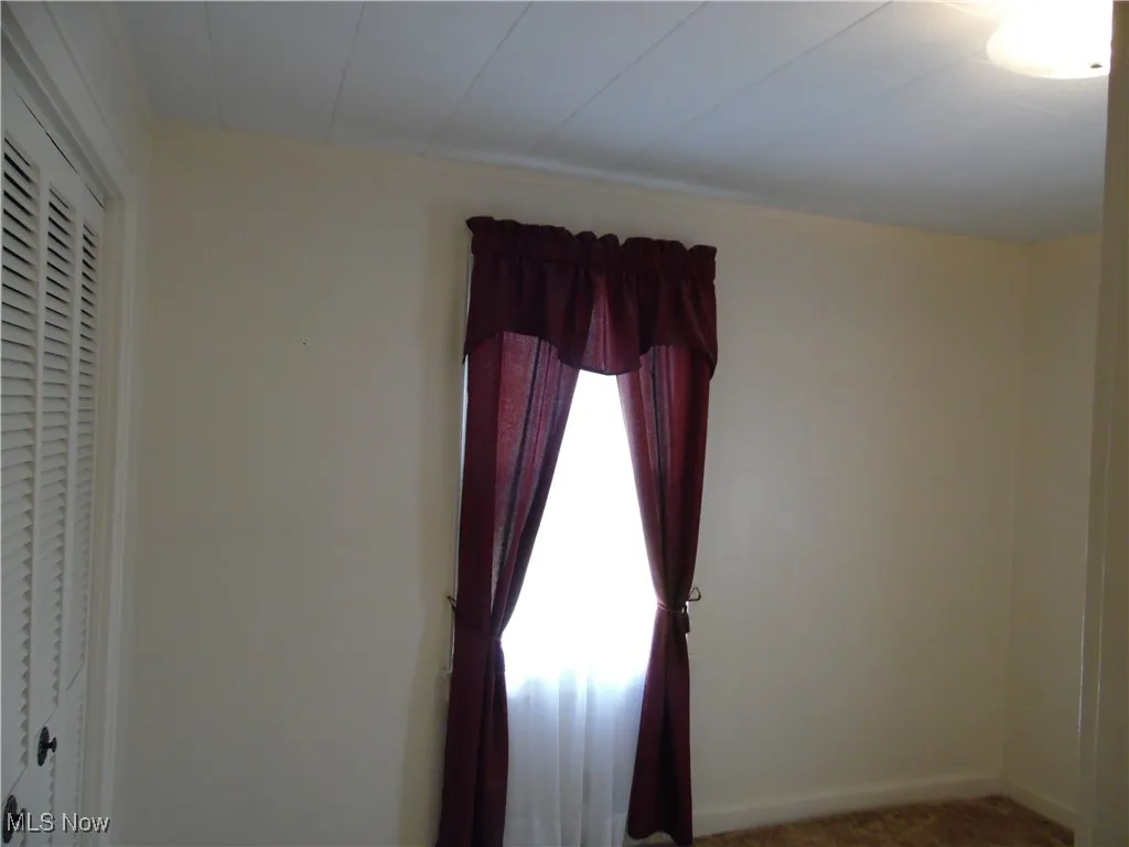 Carpeted spare room featuring baseboards