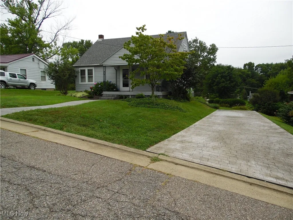 View of front of house featuring a front lawn, a chimney, and decorative driveway