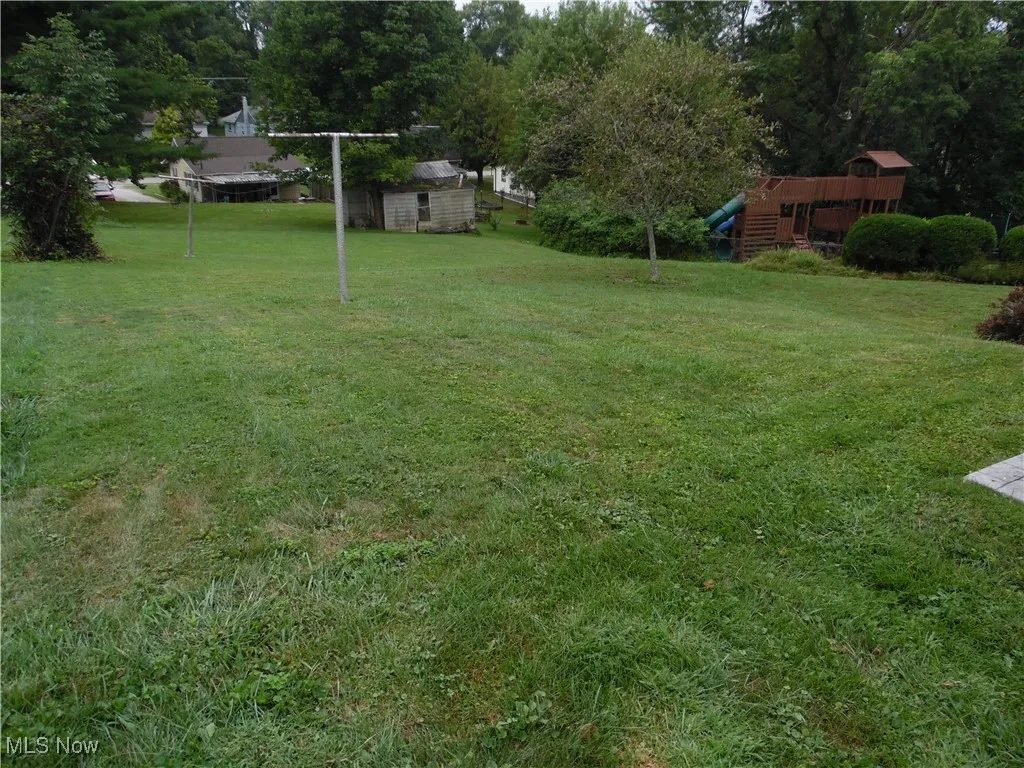 View of grassy yard featuring a storage shed and view of wooded area