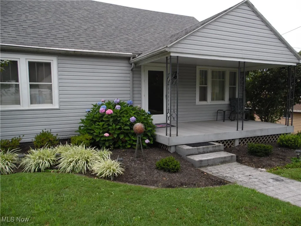 View of front facade featuring a shingled roof, a front lawn, and a porch