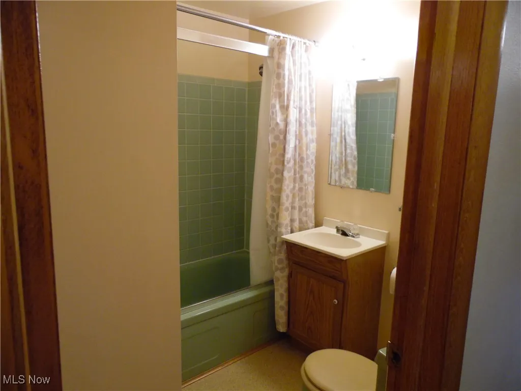 Full bathroom featuring shower / tub combo with curtain and vanity