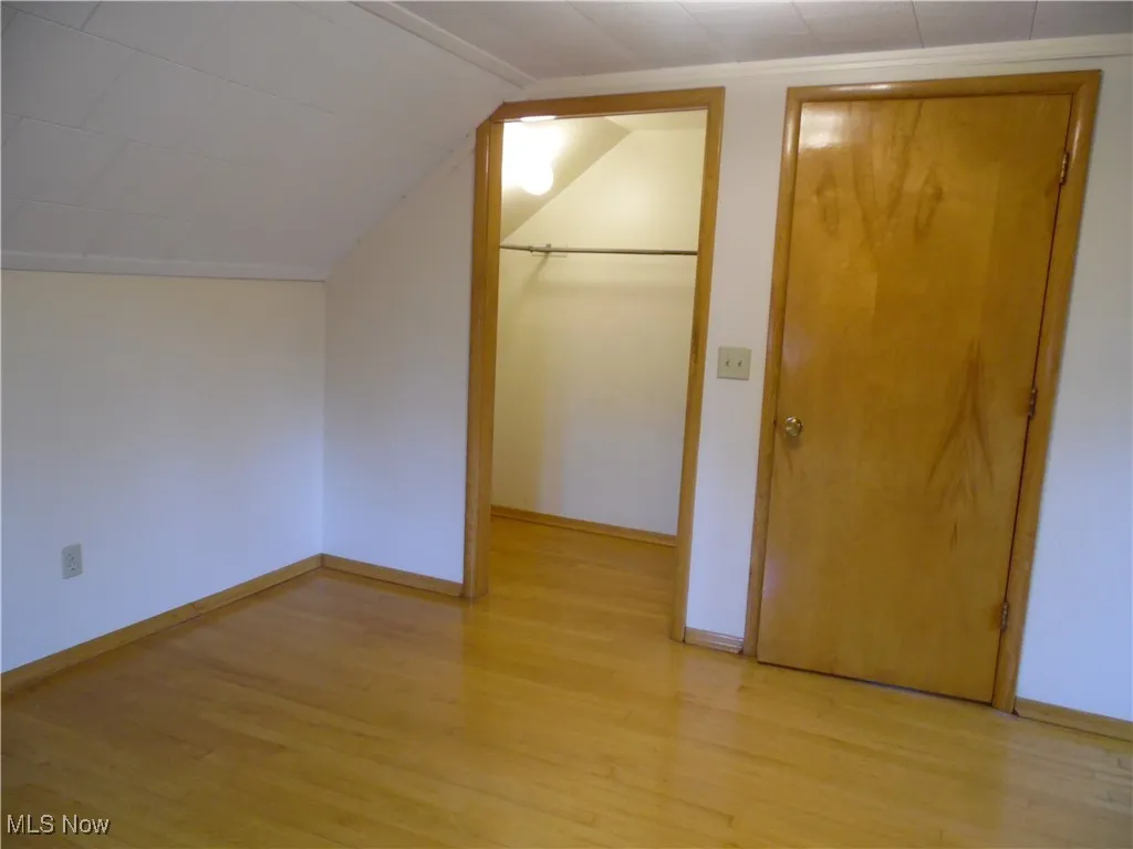 Bonus room featuring light wood-type flooring and vaulted ceiling