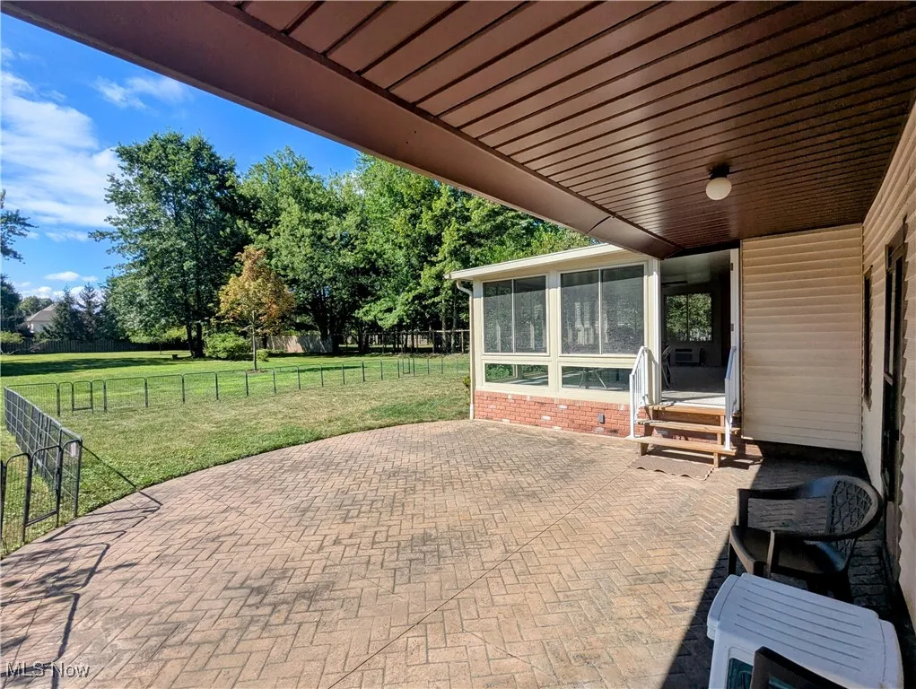 View of stamped concrete patio featuring stairs in the sunroom