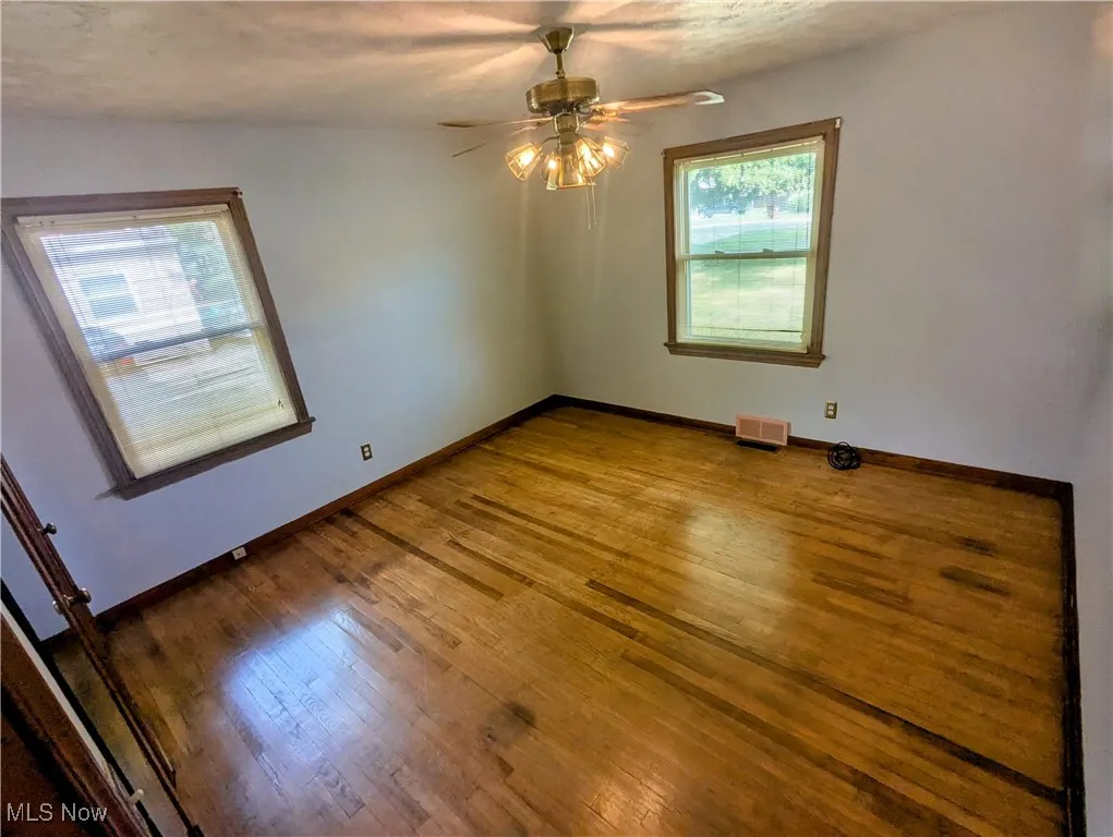 Second first floor Bedroom featuring, a ceiling fan, hardwood flooring, and his and her closets