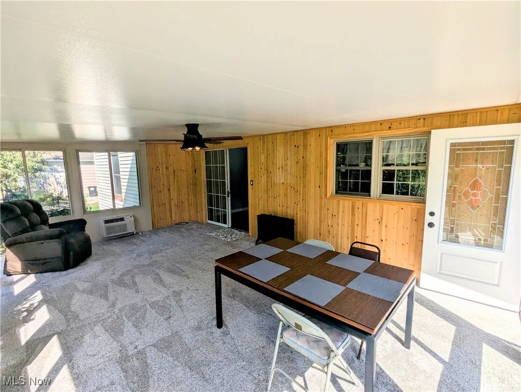 Another view of the four season sunroom featuring a ceiling fan, and carpet flooring with ceiling to floor windows overlooking the huge backyard