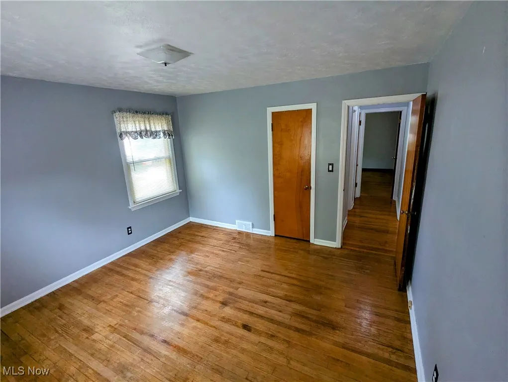 First floor Bedroom featuring hardwood flooring, a textured ceiling, and a closet
