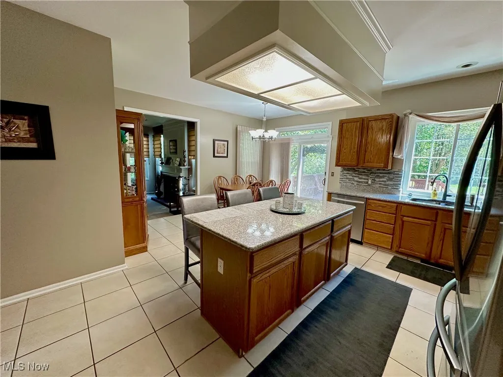 Kitchen featuring brown cabinetry, a kitchen island, a breakfast bar area, a chandelier, and appliances with stainless steel finishes