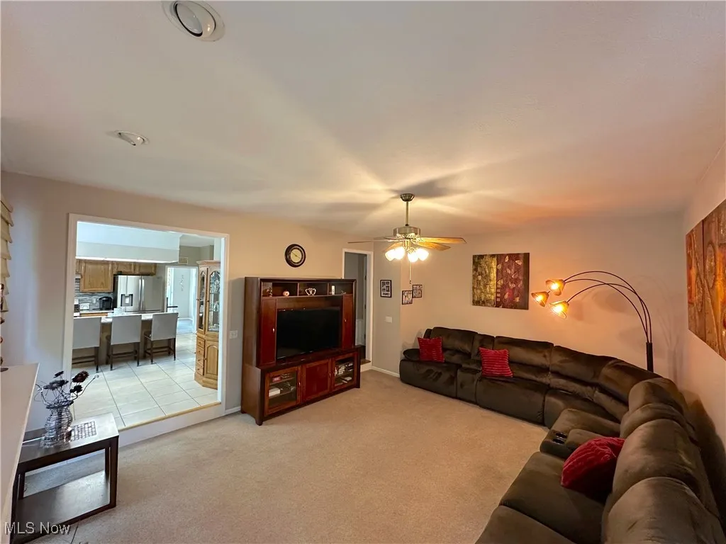 Family room with light colored carpet and ceiling fan