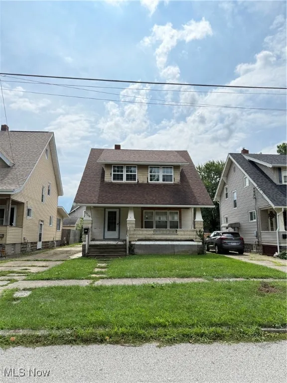 View of front facade featuring a front lawn, a porch, and a shingled roof