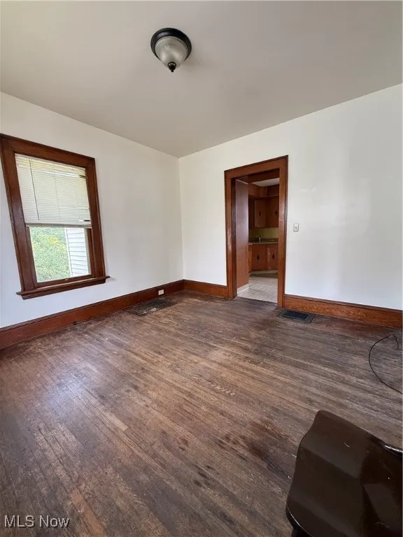 Spare room featuring baseboards and dark wood-style floors