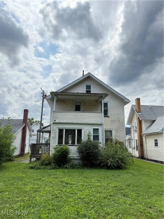 Back of house with a yard, a balcony, and a wooden deck