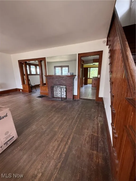 Unfurnished living room featuring dark wood finished floors and stairs