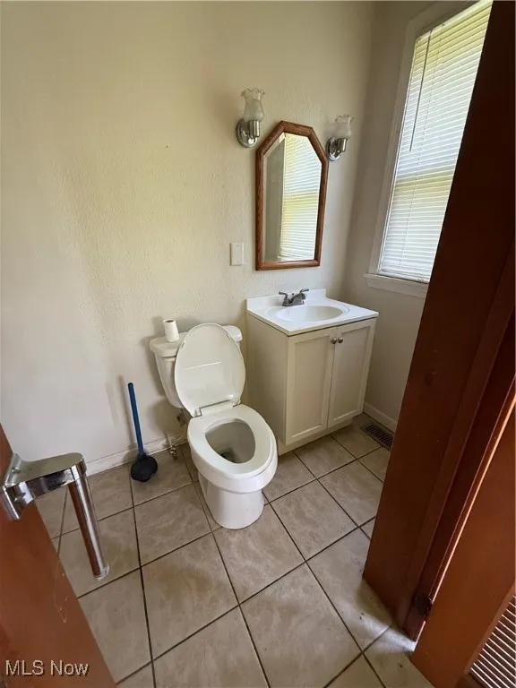 Bathroom with light tile patterned floors, vanity, and a textured wall