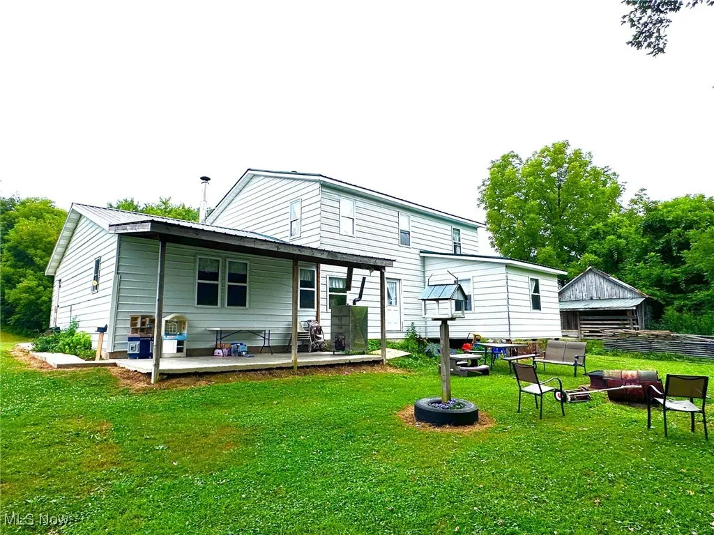 Back of property with a fire pit, a yard, and a deck