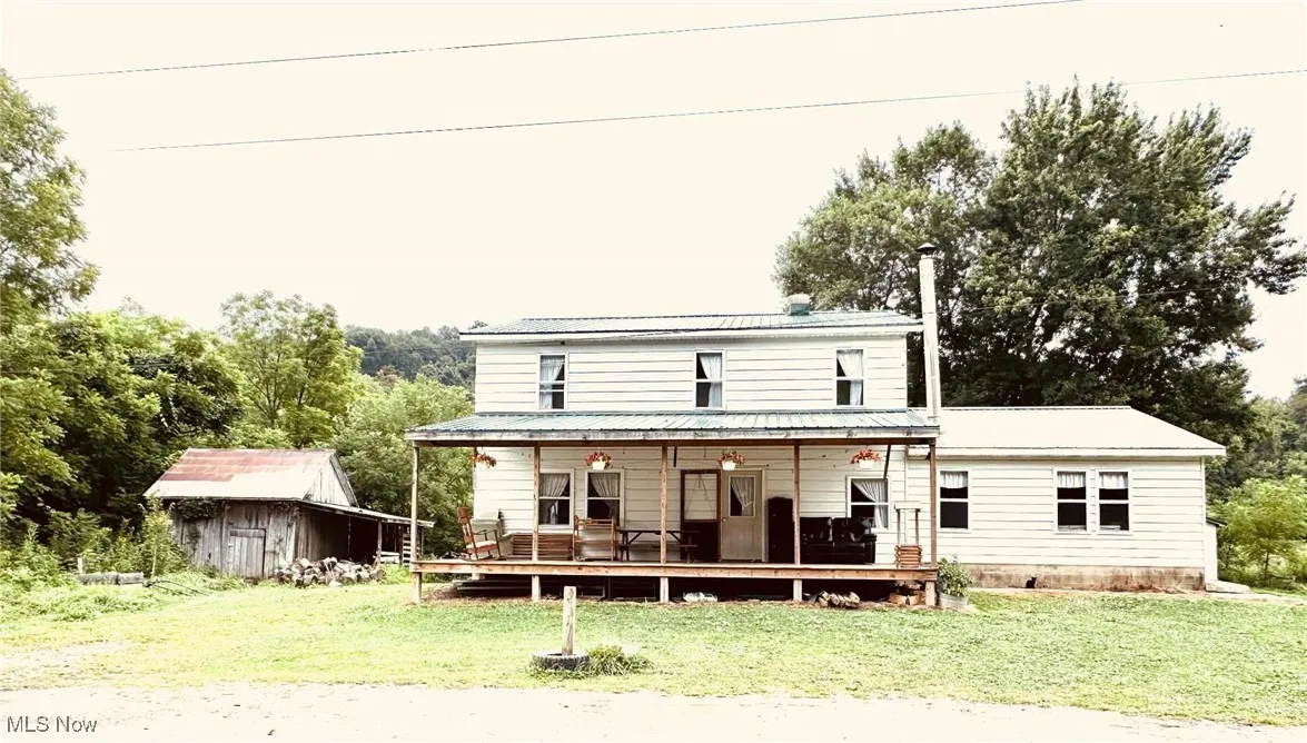 Back of property with a yard, a metal roof, a wooden deck, and a storage unit