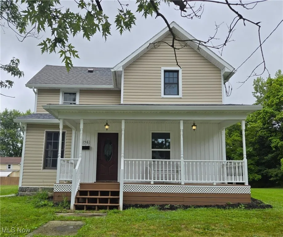 View of front facade with a porch, a front yard, and a shingled roof
