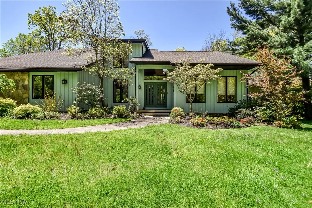 Mid-century home featuring a shingled roof, a front lawn, and board and batten siding